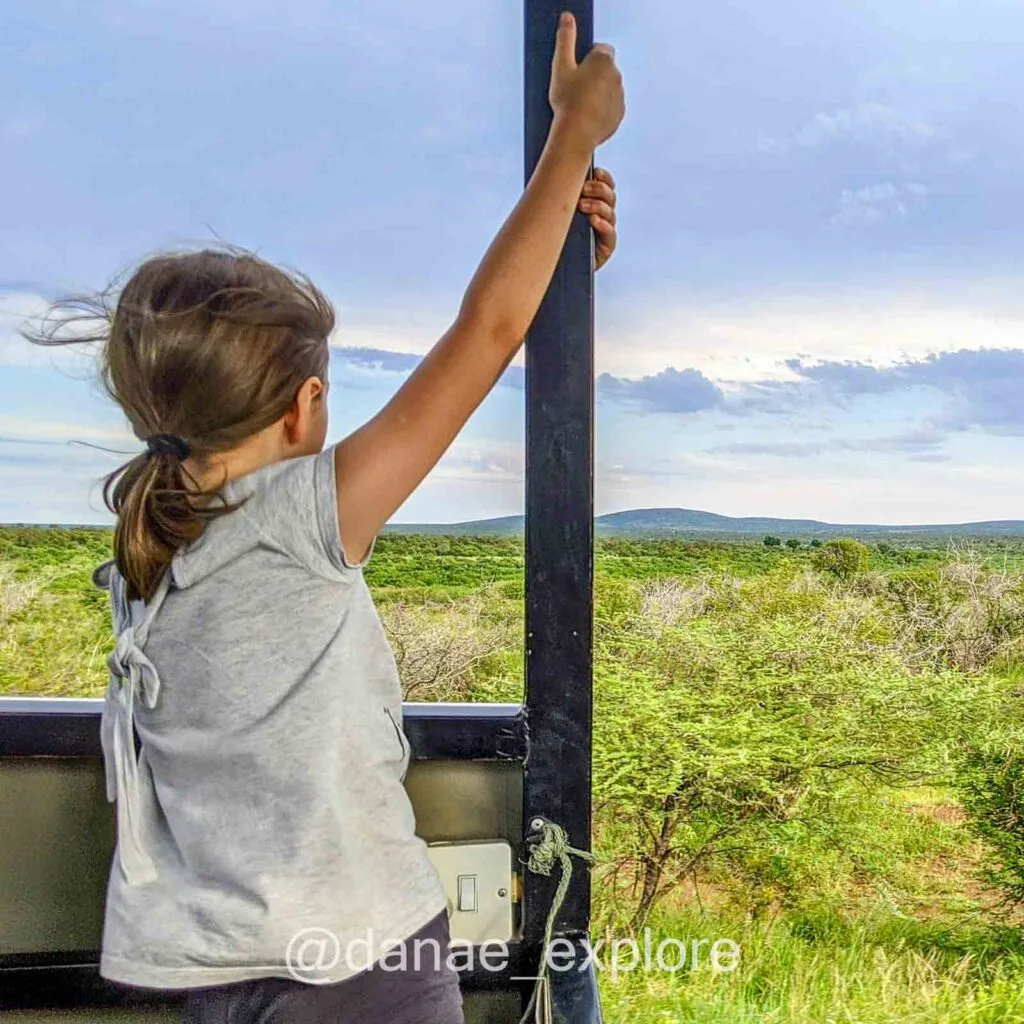 criança de costas para câmera em veículo de safari no Parque Kruger