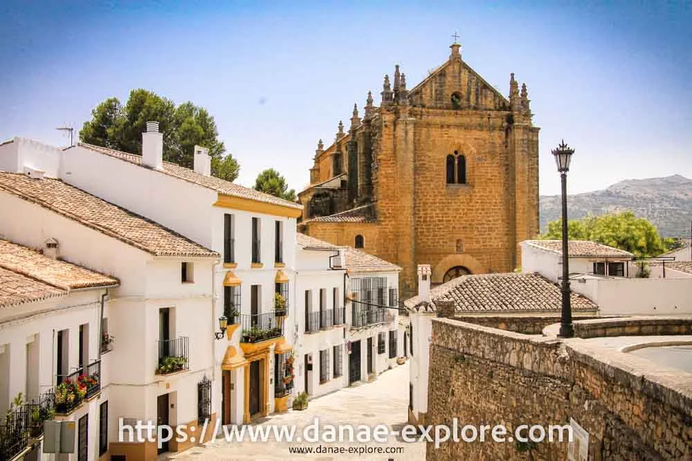 casas brancas com detalhes em amarelo, e igreja em pedra ao fundo, em Ronda, no Sul da Espanha