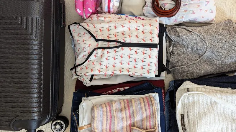 several pieces of clothing folded and separated, next to the hand luggage - tips for traveling with only hand luggage