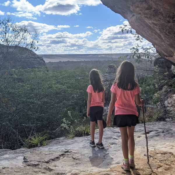 duas meninas, de costas para câmera, em mirante para a mata do cerrado, na Chapada dos Guimarães