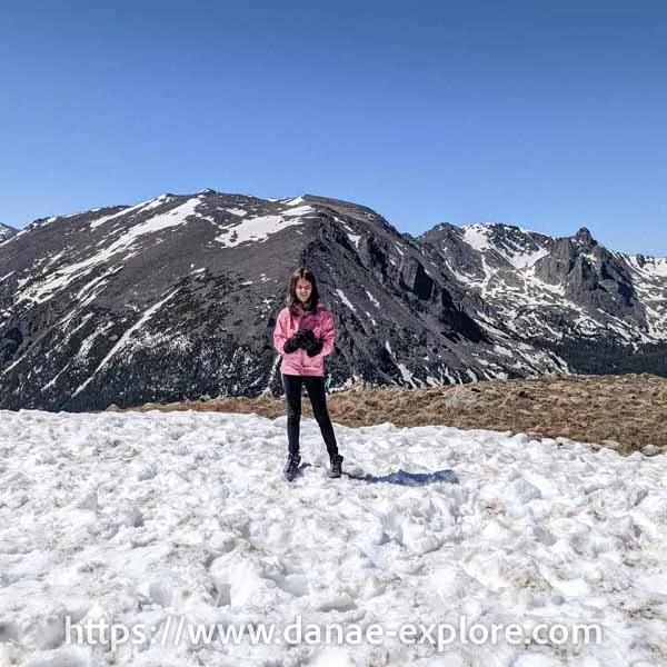 A child in a pink coat playing in the snow in Rocky Mountain National Park, on a trail in the Trail Ridge Road area