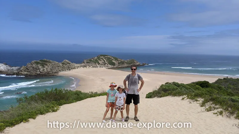 Father and two young children on top of a dune as they arrive at the beaches of Robberg Nature Reserve, Garden Route, South Africa