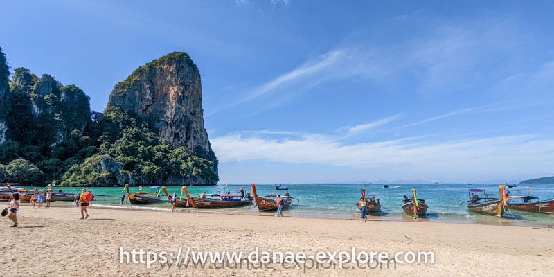 Railay Beach, Tailândia. em dia de sol sem nuvens. Há pessoas na praia e diversos barcos na água, parte de nosso roteiro de 3 semanas pelo Sudeste Asiático