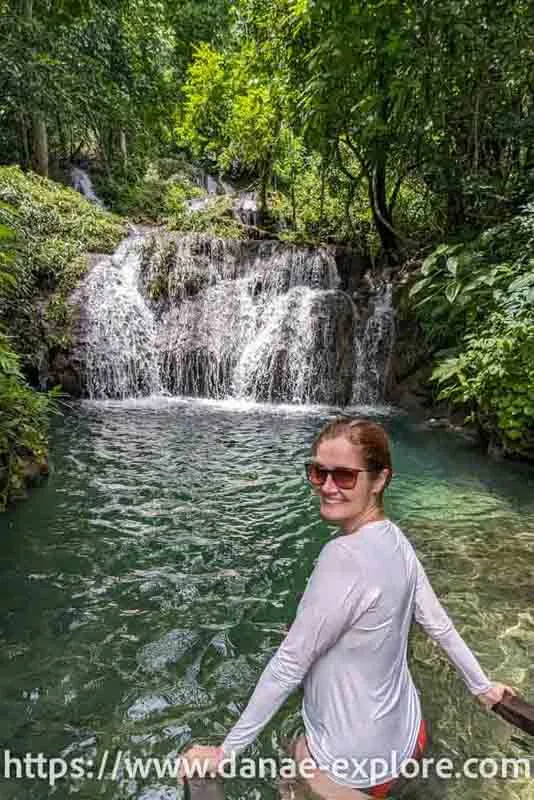 Girl in a white t-shirt and sunglasses looking at the camera, in front of the waterfall in Bonito, part of our guide with everything you need to know to visit Bonito, in Mato Grosso do Sul