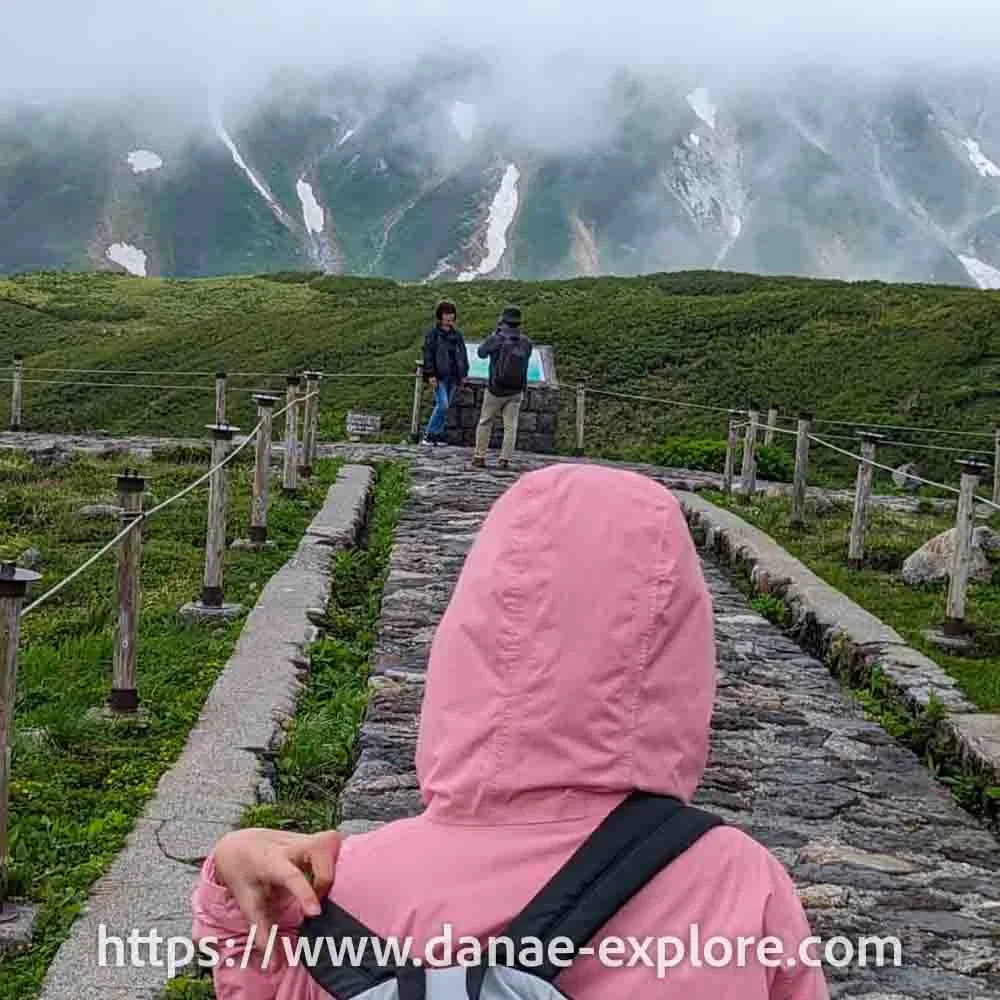 Mount Tate - Tateyama Kurobe Alpine Route - Japan - girl in pink hoodie, with her back to the camera, walking through the fog.