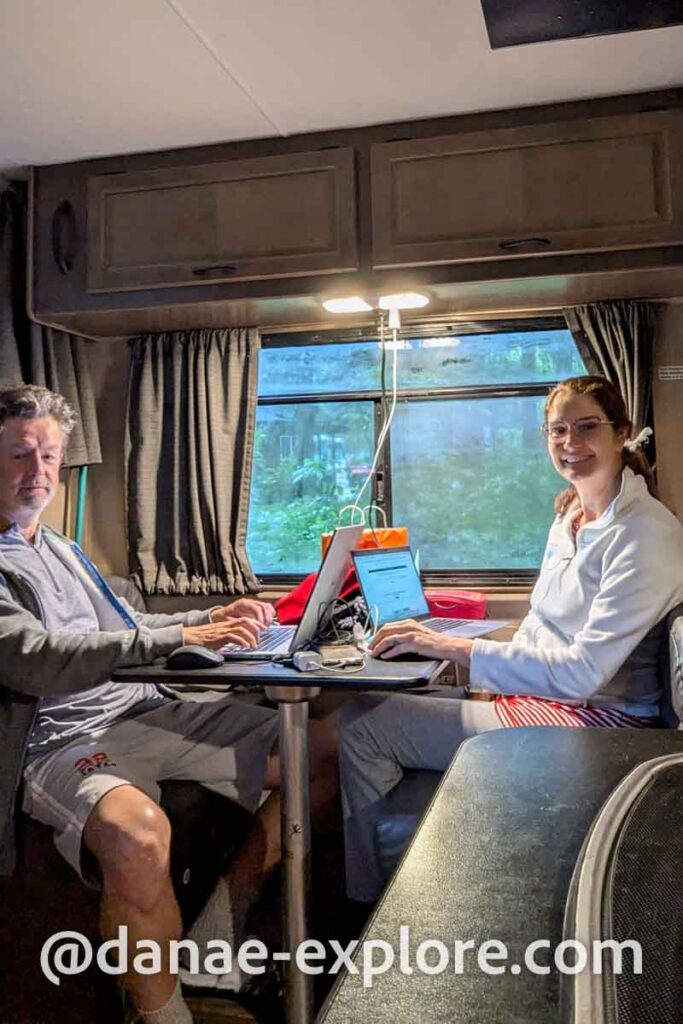 Casal trabalhando em notebook em mesa dentro de motorhome