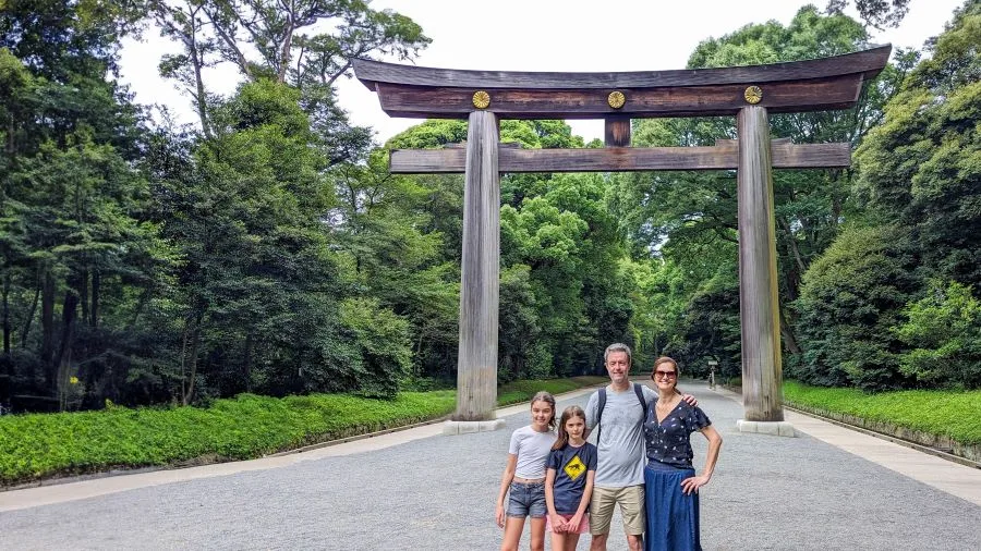Família posa em frente ao torii de madeira do Meiji Jingu, um dos santuários mais visitados de Tóquio, Japão.