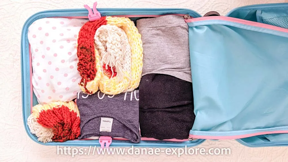 photo of open carry-on luggage, you can see organized clothing items, including a scarf and knitted hat