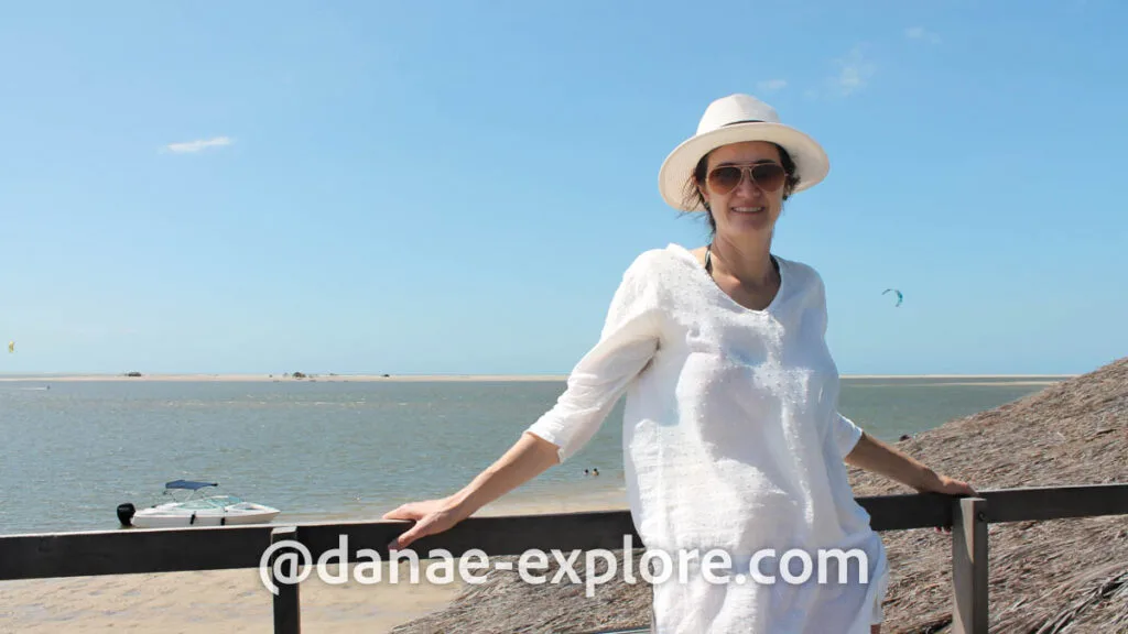 moça em roupa e chapéu branco, olhando para câmera, ao fundo o mar de Atins