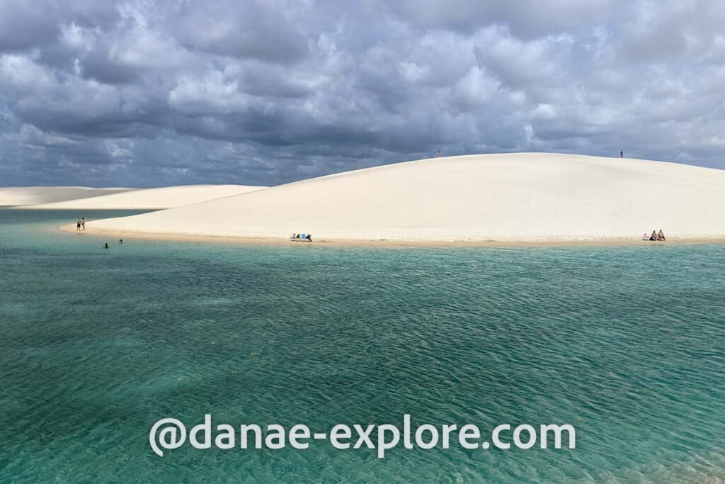 em primeiro plano, lagoa com água verde esmeralda, ao fundo dunas de areia clara, em dia nublado, em Lençóis Maranhenses, próximo a Santo Amaro do Maranhão