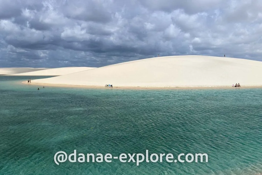 em primeiro plano, lagoa com água verde esmeralda, ao fundo dunas de areia clara, em dia nublado, em Lençóis Maranhenses, próximo a Santo Amaro do Maranhão