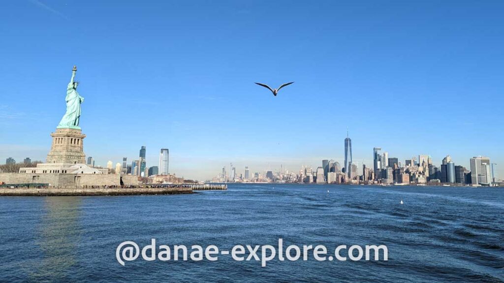 vista de Nova Iorque do barco que leva ao tour da Estátua da Liberdade: a esquerda está a estátua e ao fundo, a direita, a ilha de Manhattan