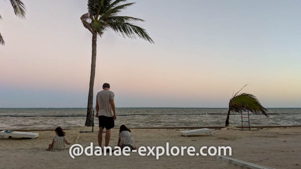 Homem e duas meninas brincam na praia ao por-do-sol em San Pedro, em Belize