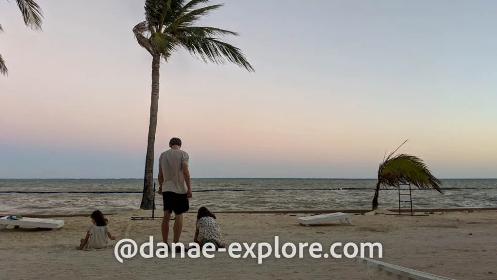 A man and two girls play on the beach at sunset in San Pedro, Belize