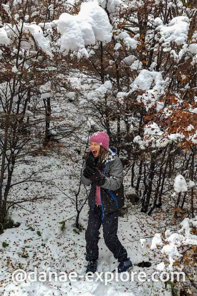 Child playing in the snow in Ushuaia, among trees with lots of snow on the branches