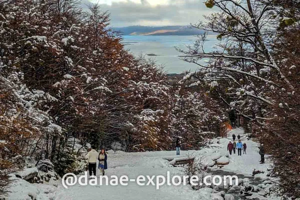 People walking through Cerro Martial in autumn, already covered in snow. In the background you can see part of the Beagle Channel