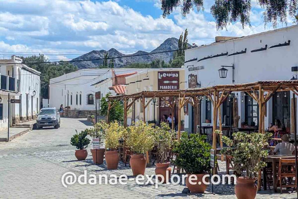 Restaurante com mesas na calçada, em rua com casas brancas, em Cachi, parte de nosso roteiro pelo norte da Argentina