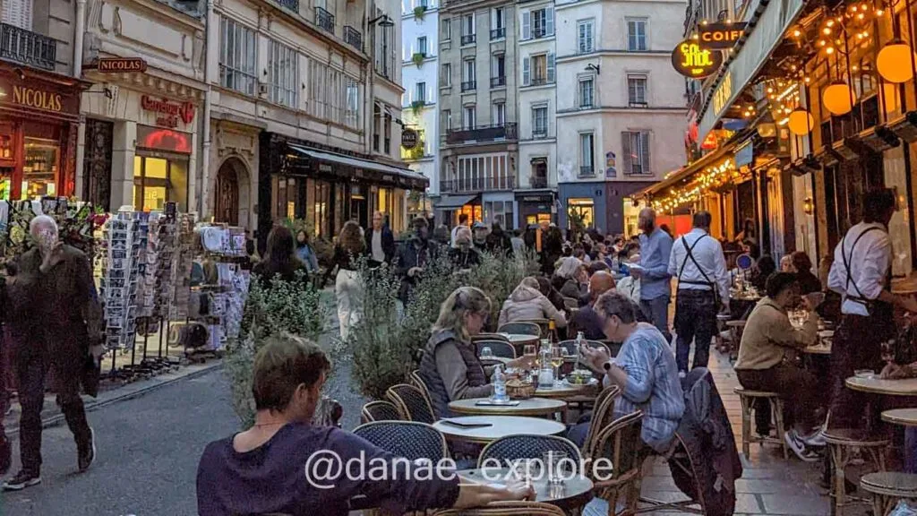 People eating at sidewalk cafes in Paris in the late afternoon.