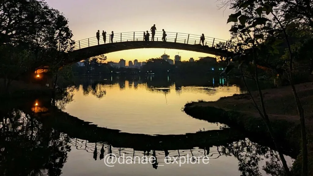 Sunset at Ibirapuera Park, in São Paulo. Photo of the lake with a bridge where people are walking.