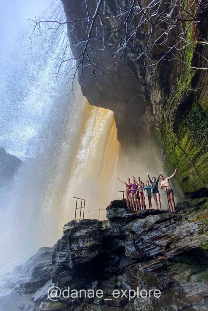 Grupo de pessoas atrás da queda d'água na Cachoeira de São Romão, no Parque Nacional da Chapada das Mesas, Maranhão