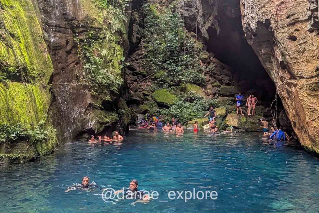 Pessoas nadando no Encanto Azul, um poço de água azul turquesa, cercado por paredões de rocha com vegetação