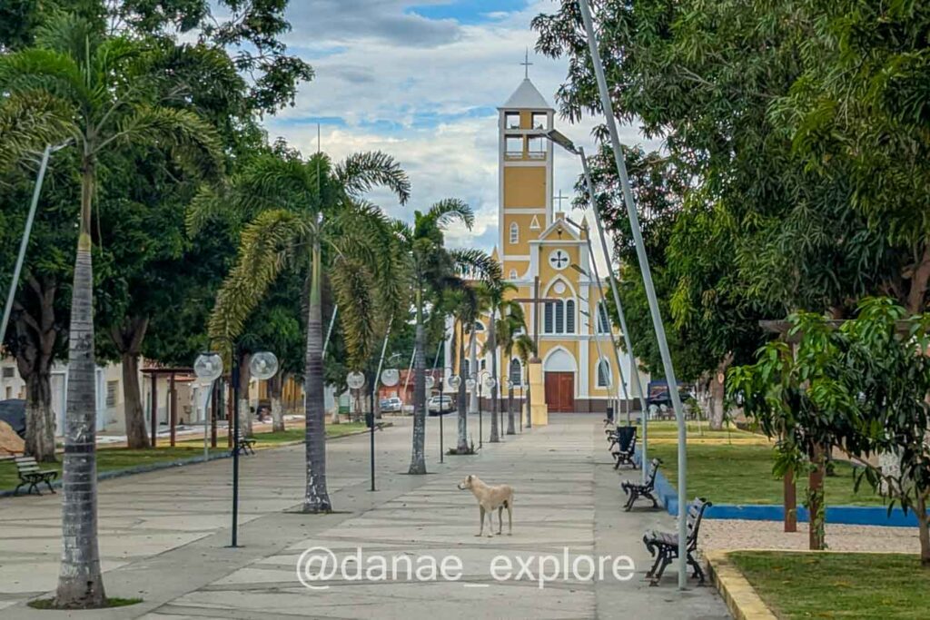 Vista de praça em Carolina, no Maranhão; ao fundo há uma igreja amarela. Há um cachorro caramelo em primeiro plano