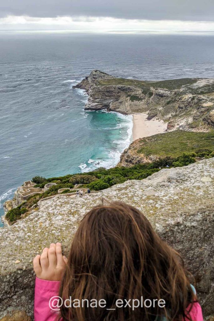 Criança de costas para a câmera observando o Cabo da Boa Esperança do alto de um mirante