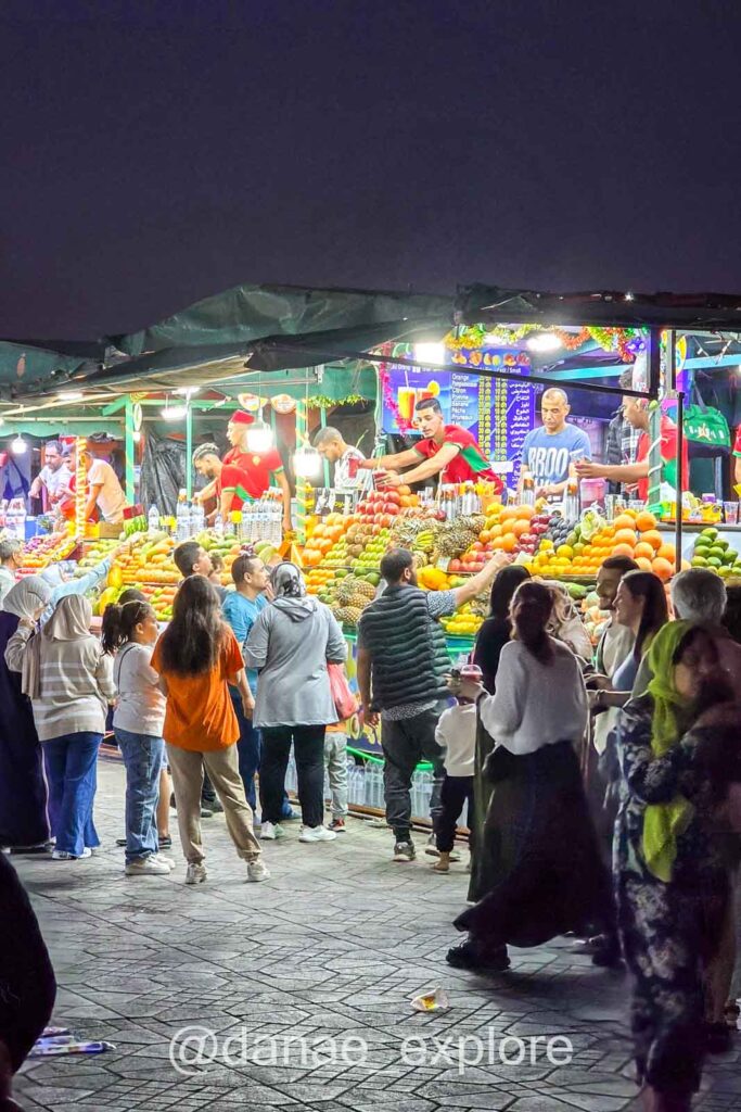 Barracas de sucos na Praça Jemaa El-Fnaa, em Marrakesh, à noiitte, com diversas pessoas transitando e comprando