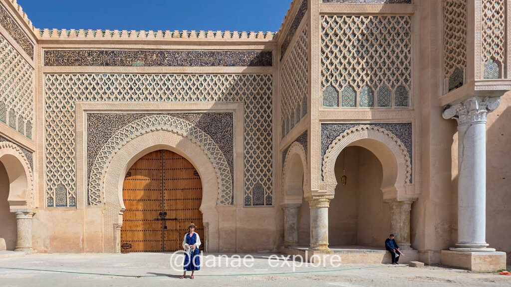 moça em vestido azul em frente a Porta Bab Mansur, em Meknes, Marrocos
