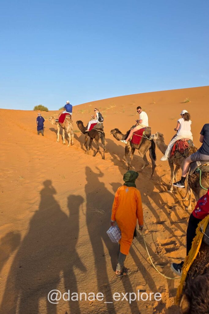 Turistas fazendo passeio em dromedários no deserto do Saara, próximo a Merzouga
