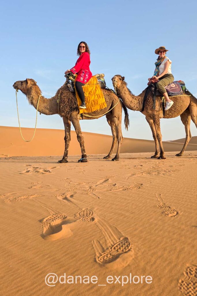 Duas moças (eu e minha companheira de viagem), montadas em dromedário, em passeio no deserto do Saara, Marrocos