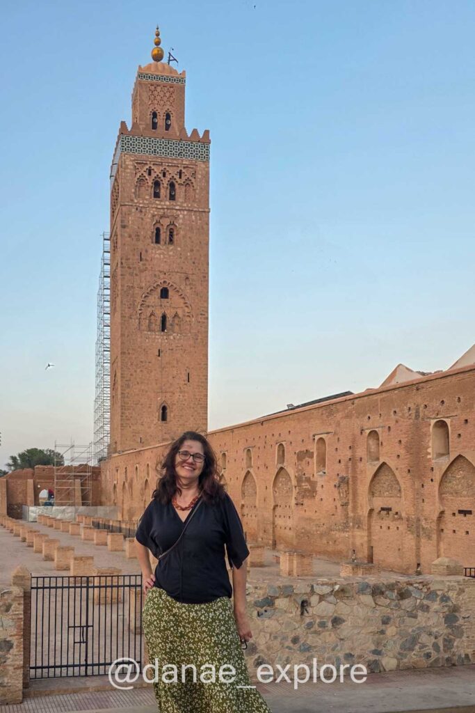 mulher, em saia longa e camiseta, viajando sozinha pelo Marrocos, na foto ela está do lado externo da Mesquita Koutoubia, em Marrakesh - dicas do que vestir no Marrocos