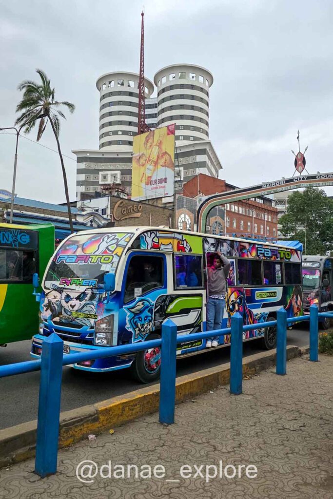 Ônibus com pintura em grafiti colorido transitando por Nairobi, capital do Quênia, em dia nublado