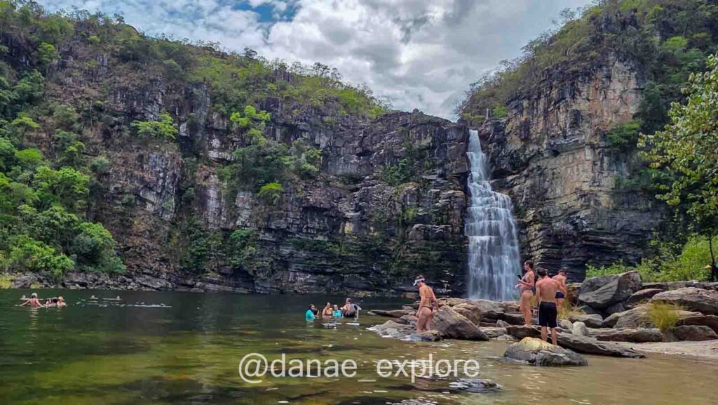 Turistas nadam e descansam em pedras diante da Cachoeira do Garimpão, na trilha amarela do Parque Nacional da Chapada dos Veadeiros.