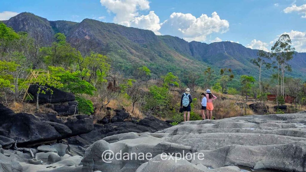 Três pessoas (meu marido e filhas) exploram o Vale da Lua, ao fundo as montanhas da Chapada dos Veadeiros