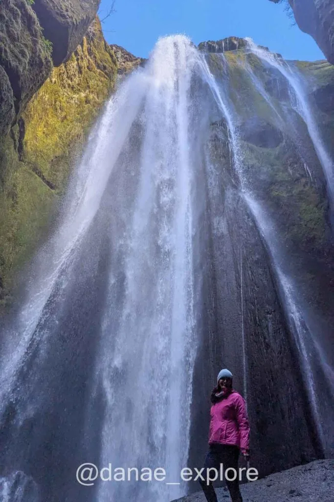 Me at the base of Gljúfrabúi Waterfall, hidden between rock walls, one of the most beautiful waterfalls to visit in Iceland.