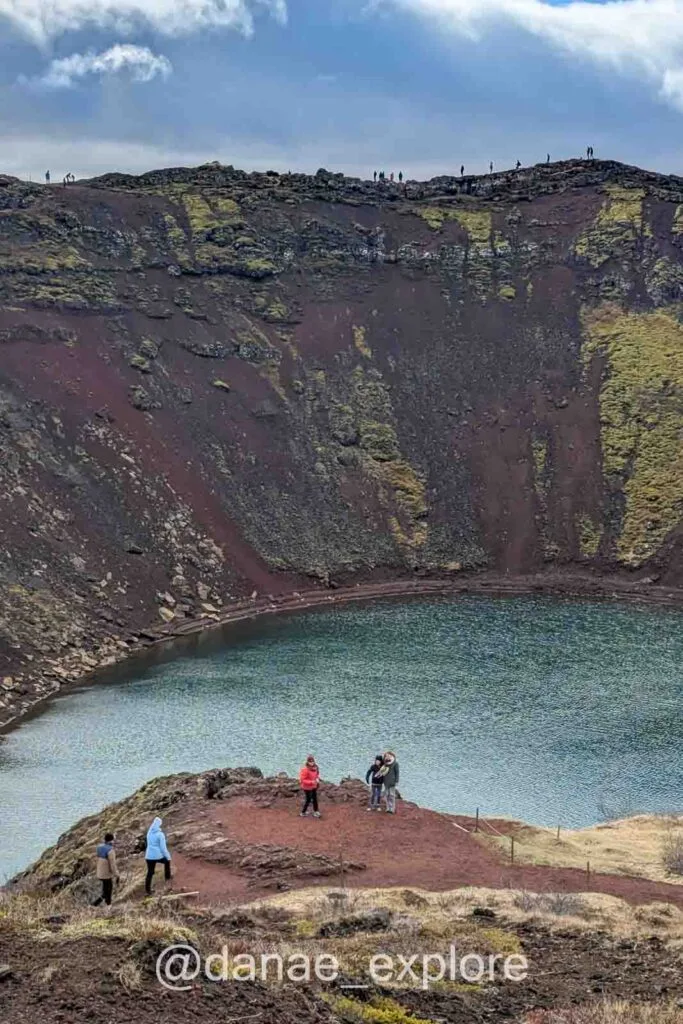 Kerid volcanic crater with a blue lake at its center, visitors walking on the rim, one of the attractions of the Golem Circle in Iceland.
