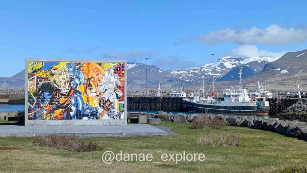 Olafsvik village, with a view of the harbor with fishing boats and snow-capped mountains in the background.