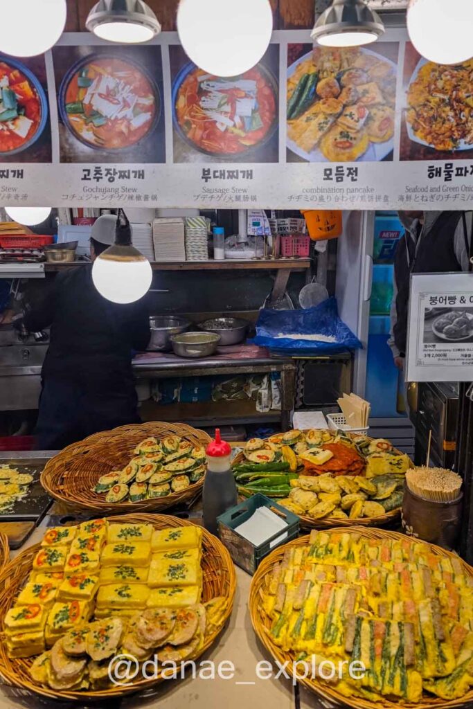 Street food em mercado coreano com pratos típicos como jeon e preparos à vista