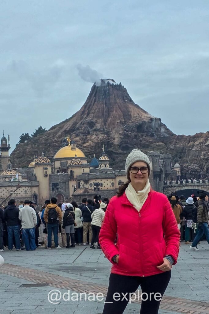 eu, com casaco, gorro e cachecol, em frente ao Vulcão do Tokyo DisneySea, na área de Mediterranean Harbor 