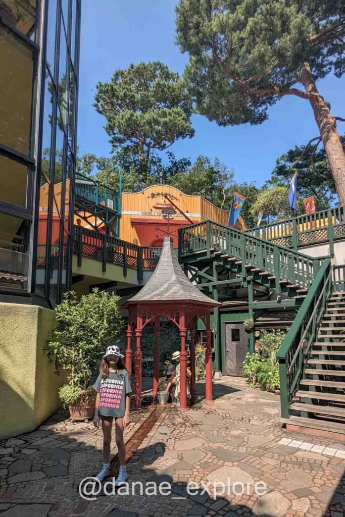 menina posa para foto na área externa do Museu Ghibli em Mitaka durante bate-volta de Tóquio, é um dia quente com sol 