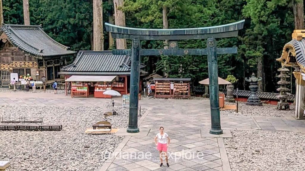 eu com shorts rosa e blusa branca em frente a Torii do santuário Toshogu em Nikko, um dos bate-volta de Tóquio que mais gostei