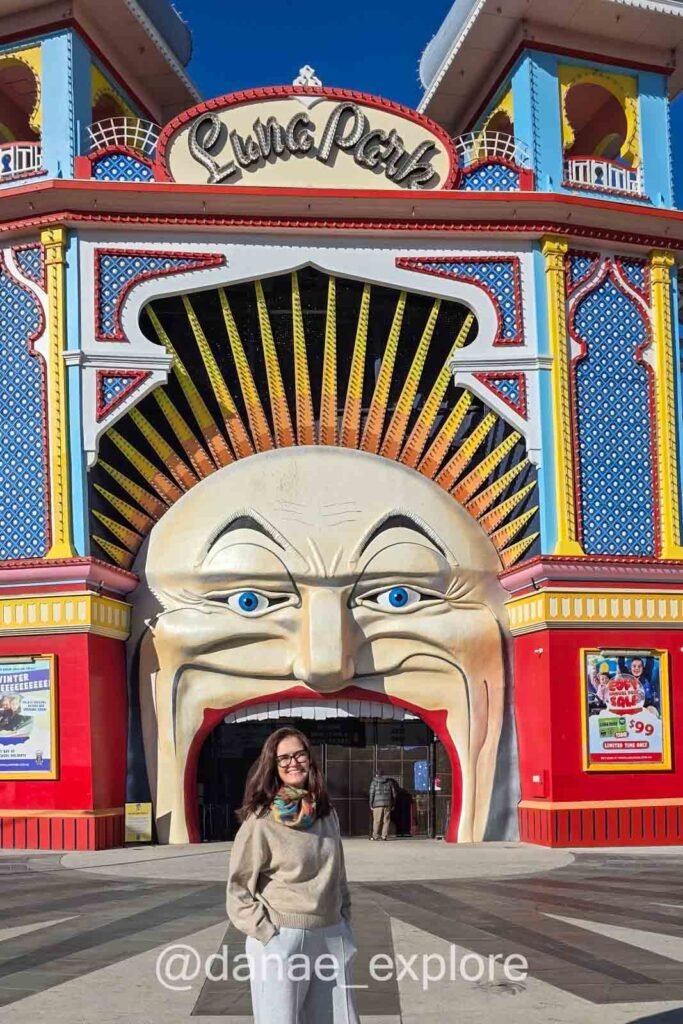 Eu na entrada do Luna Park, em Melbourne, o parque de diversões mais antigo em funcionamento contínuo do mundo