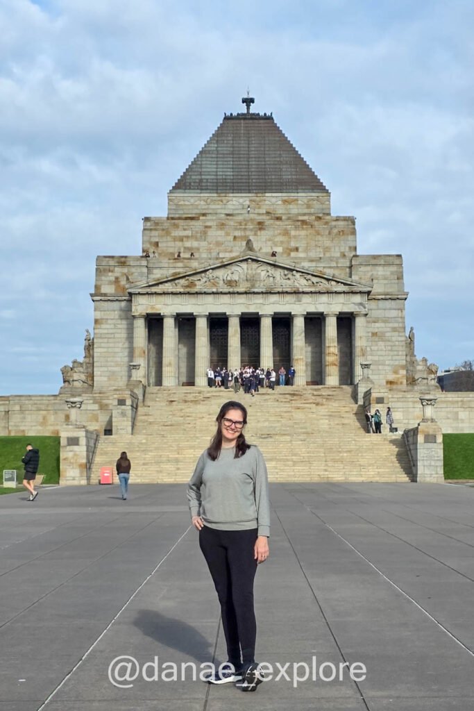 me, in black trousers and a gray top, in front of the Shrine of Remembrance on a cloudy day in Melbourne