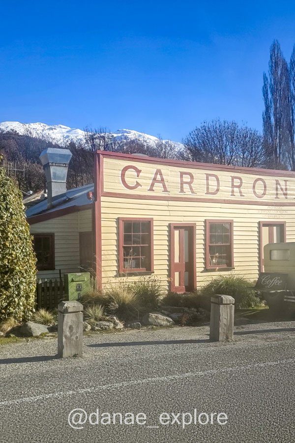 Fachada de madeira com o letreiro Cardrona e montanhas nevadas ao fundo.