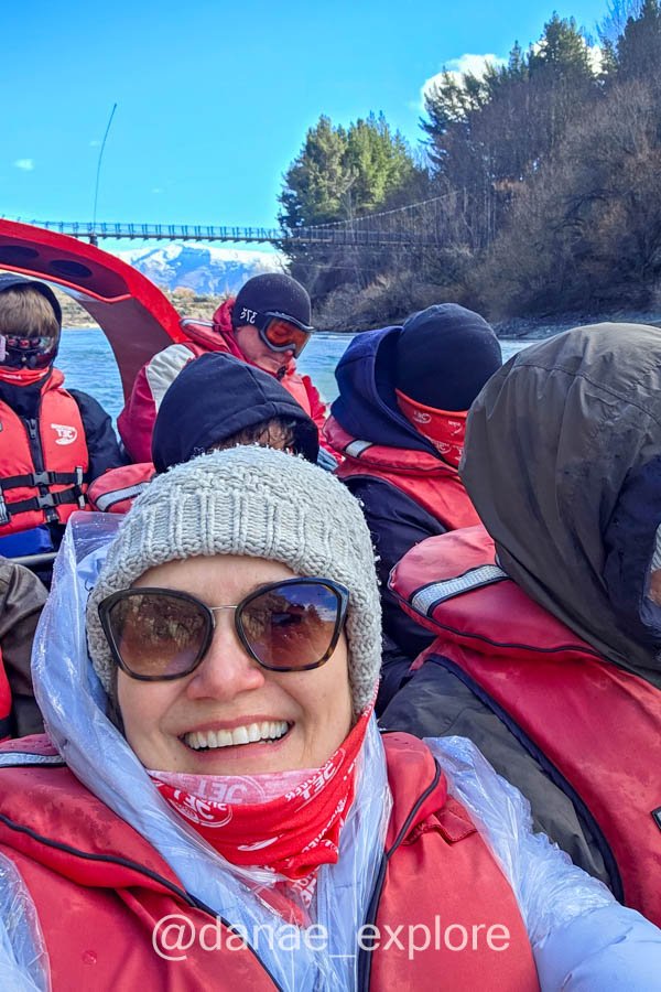 Dânae e outros passageiros de colete salva-vidas a bordo de um jet boat no rio Shotover, minha atividade radical preferida em Queenstown