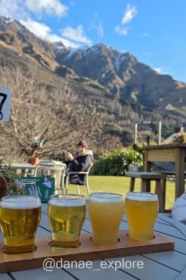 Degustação de quatro cervejas em uma mesa ao ar livre, com montanhas ao fundo, na Canyon Brewing próximo ao Shotover Jet em Queenstown
