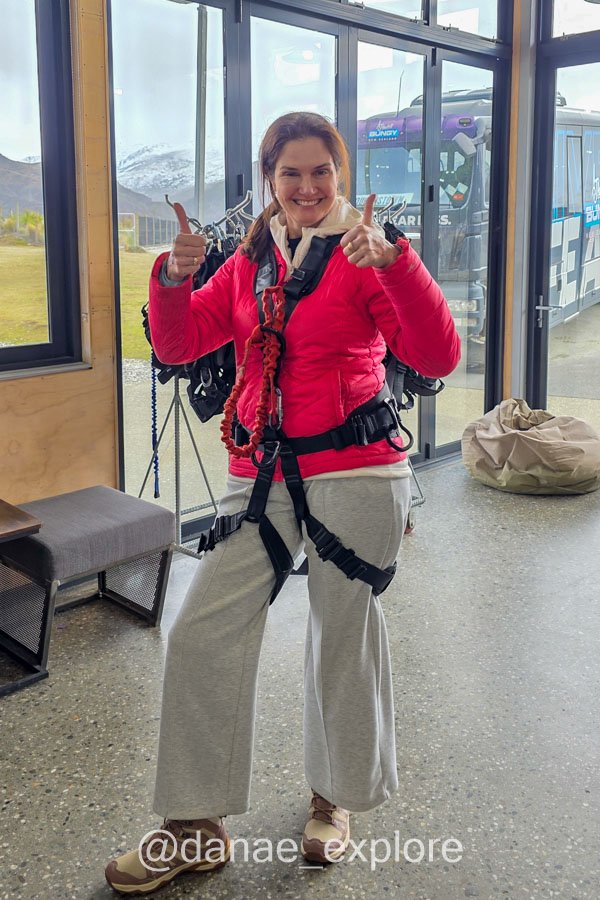 Eu sorrindo e fazendo sinal de positivo (apesar de claramente apavorada) usando o equipamento de segurança do Nevis Swing.